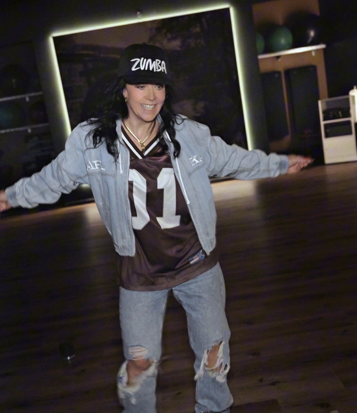 Elena tanzt im Studio, mit Zumba-Cap und Jeansjacke